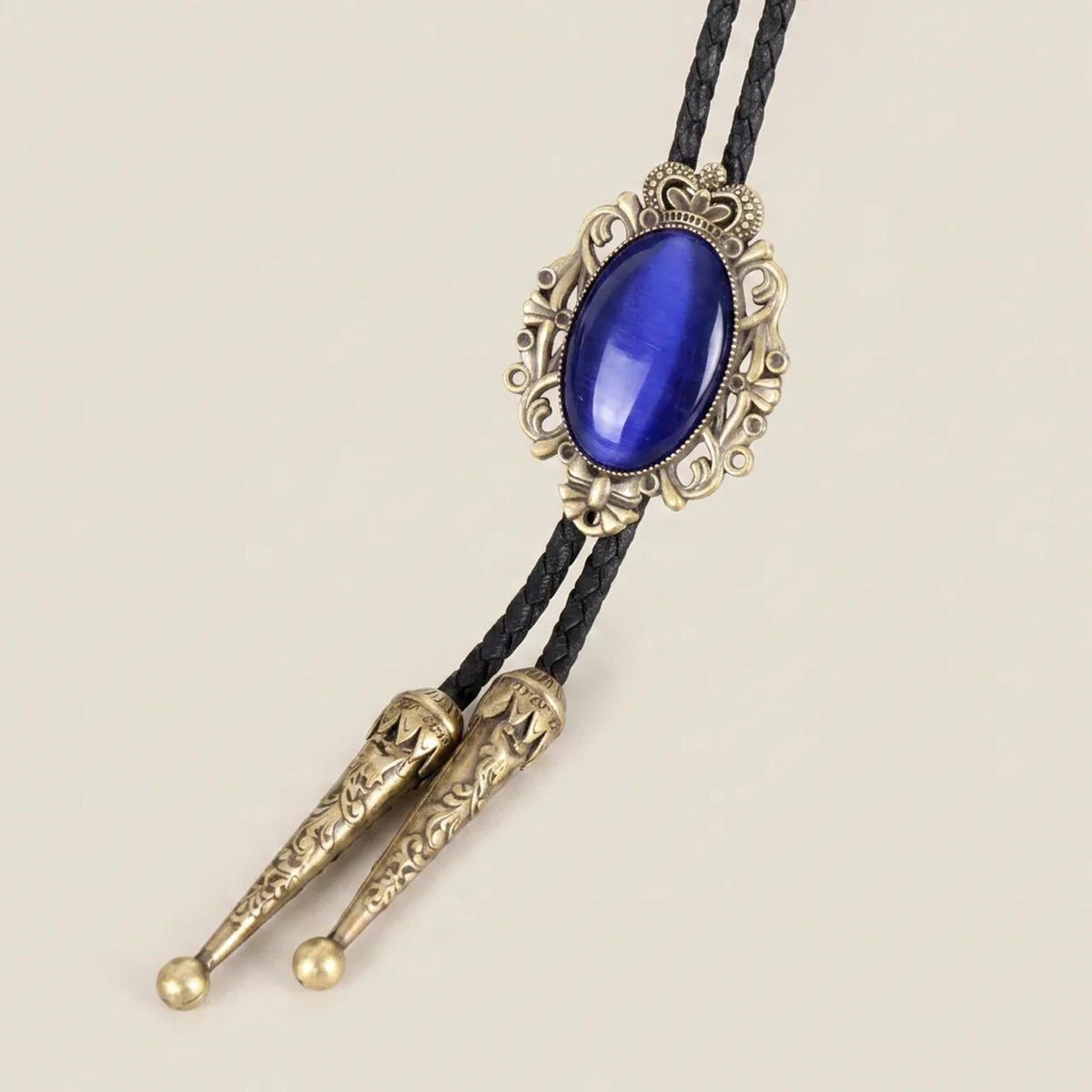 Front view of bolo tie necklace featuring royal blue cat eye stone and antique bronze metal crown design