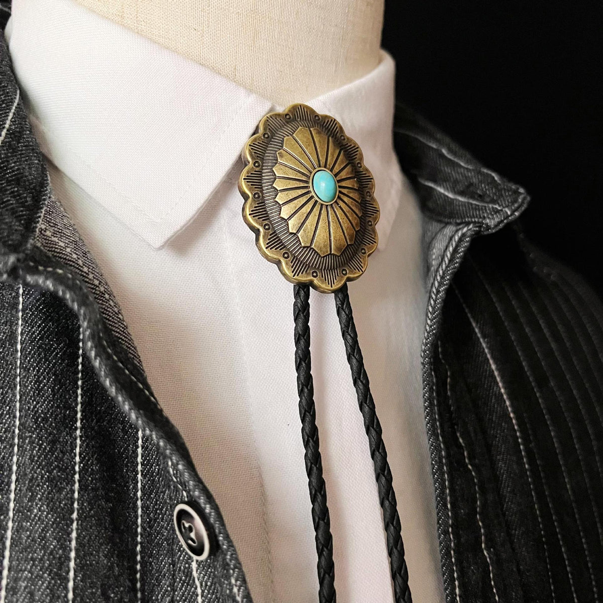 Three-quarter close-up of polished metal checkered vintage silver feather pendant western bolo tie showing clasp and feather pendant details