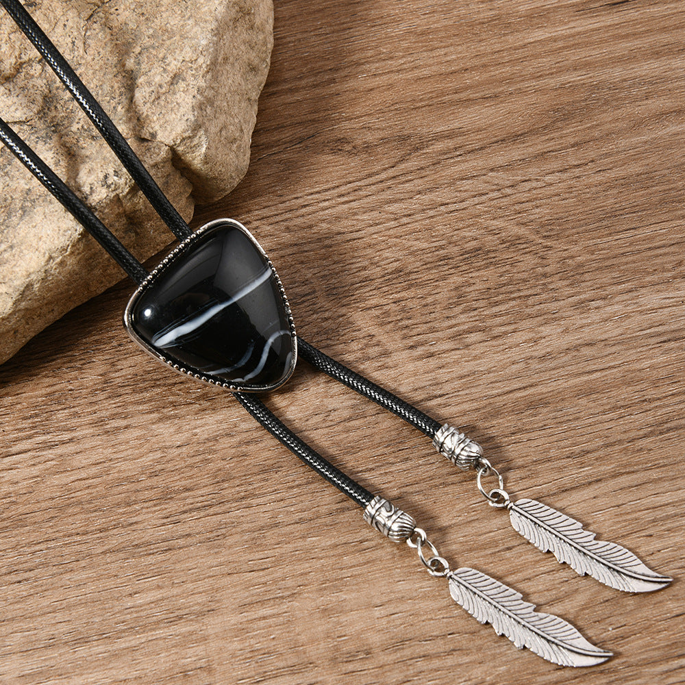 Black triangle crystal inlay pendant necklace shown at three-quarter angle with minimalist background