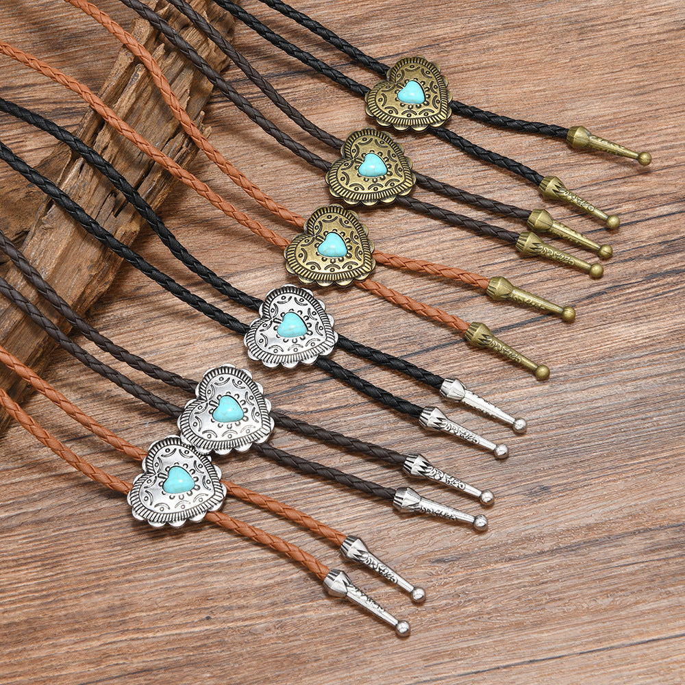 Three-quarter close-up of turquoise heart pendant with braided deep coffee leather showing white K accent details